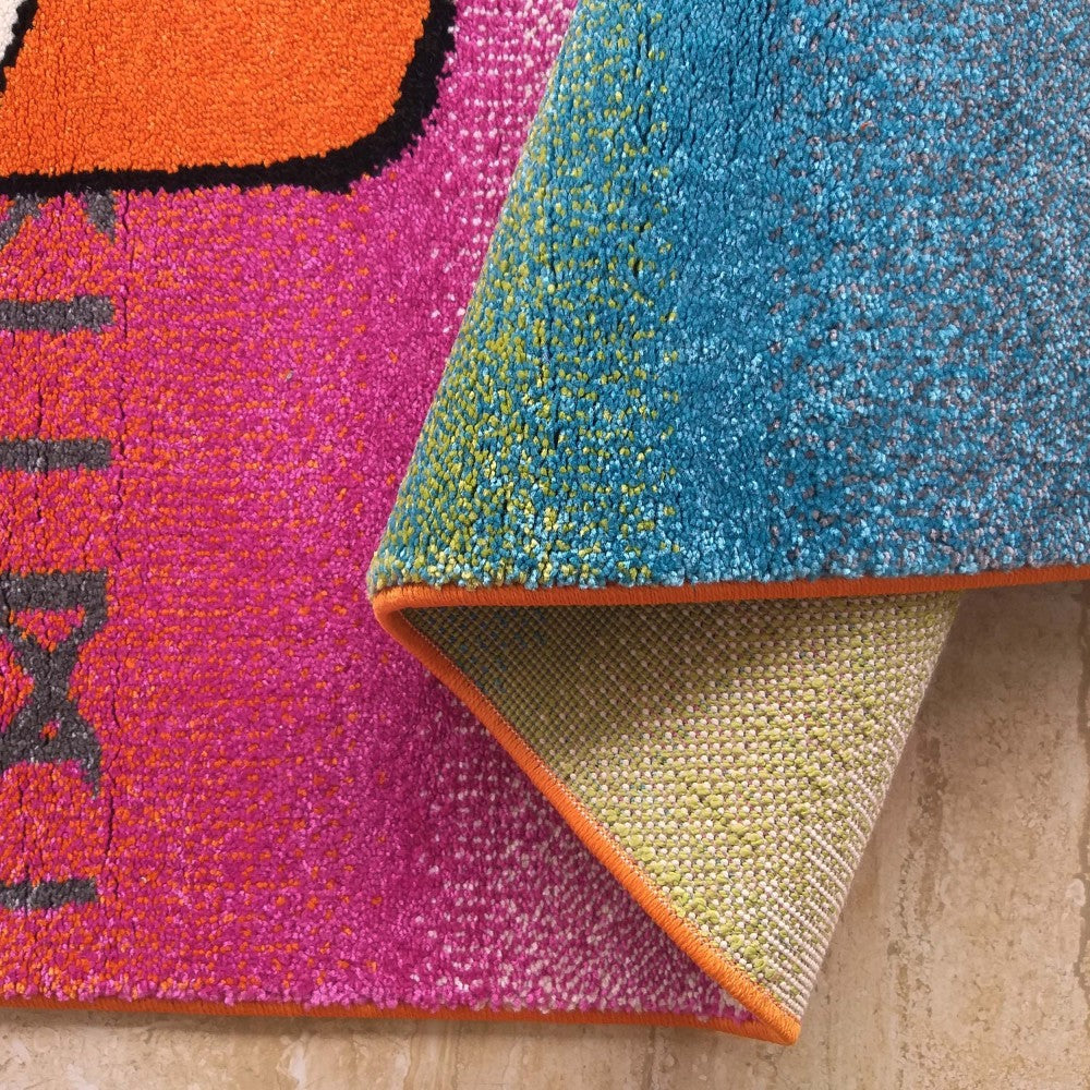 Tapis coloré à poils longs partiellement enroulé. On distingue ses zones fuchsia à motifs, bleu turquoise moucheté, et son dos tissé beige avec bord orange