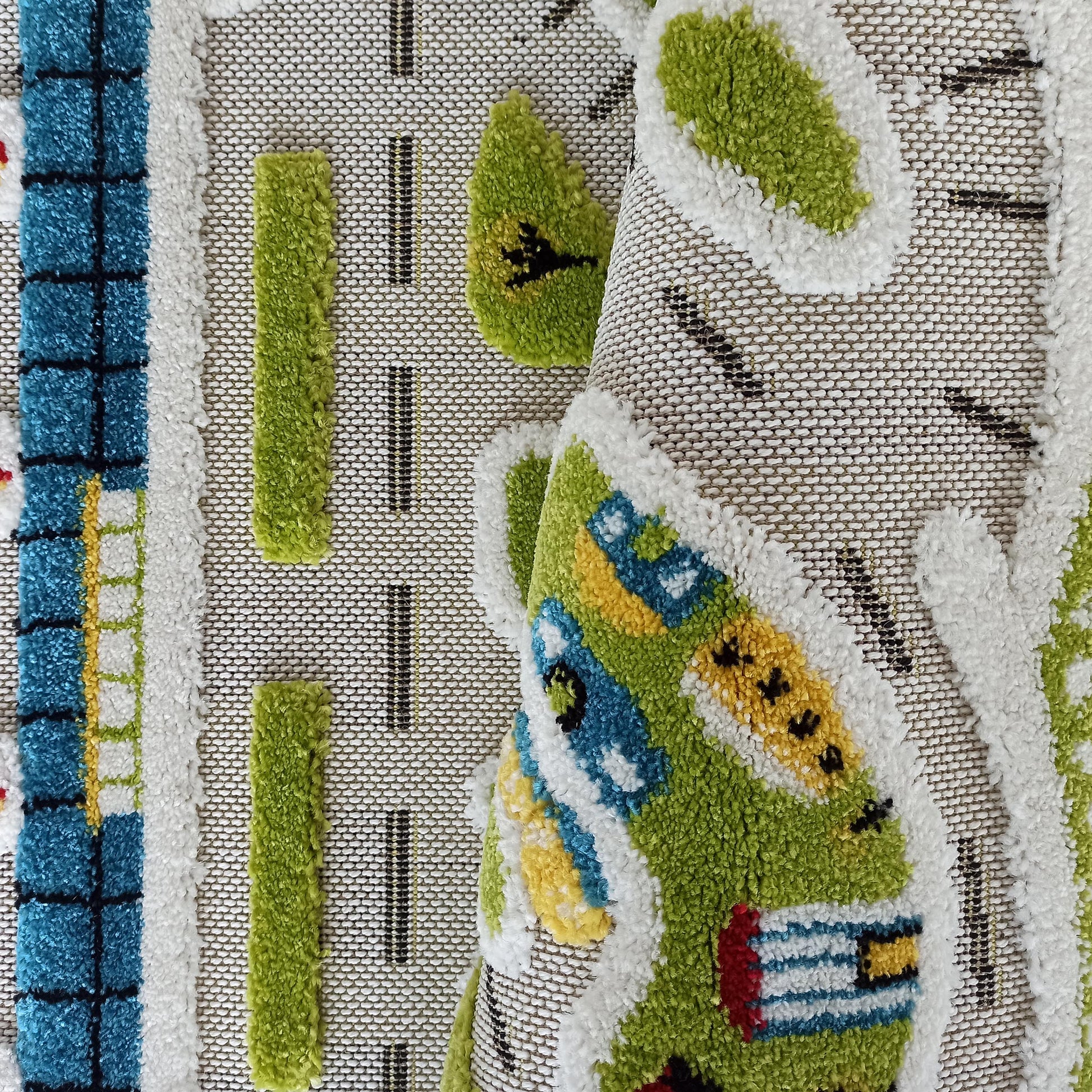 Tapis en relief avec des motifs colorés de routes, arbres et bâtiments en vert, bleu, blanc, jaune et noir