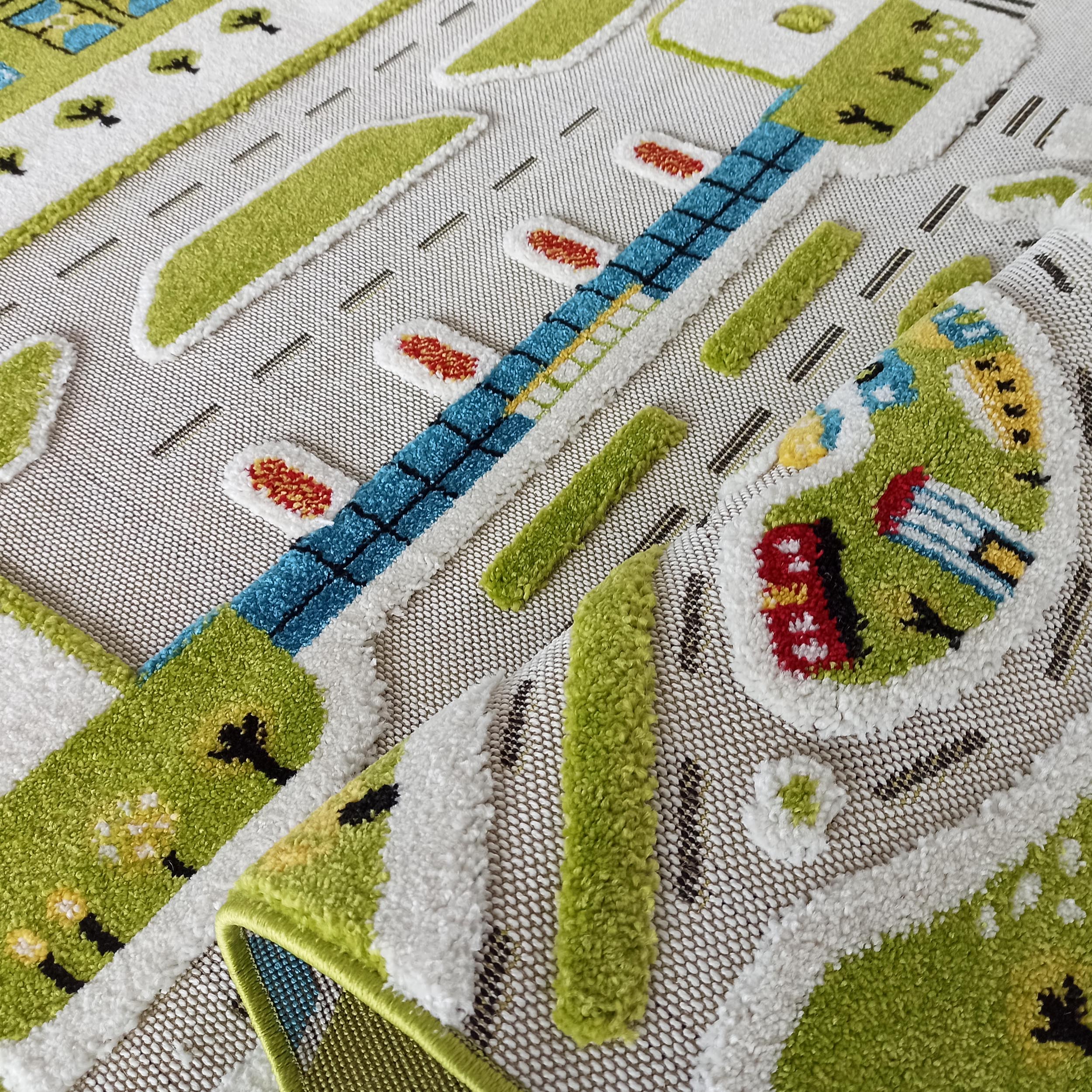 Tapis coloré pour enfant avec un motif de ville en relief: routes grises, herbe verte, bâtiments bleus, rouges et jaunes. Un coin est relevé