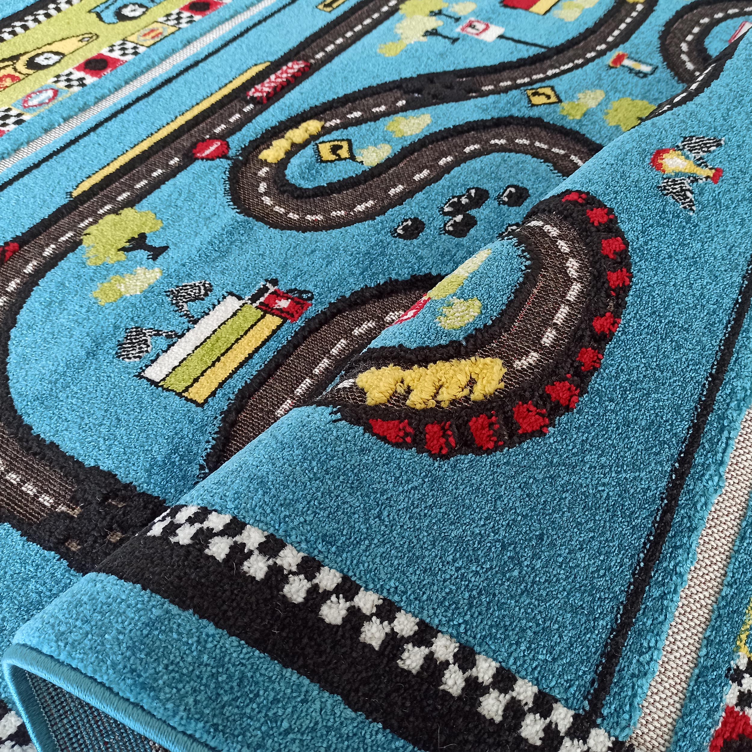 Gros plan d'un tapis enfant bleu turquoise, partiellement enroulé, décoré de motifs de routes, de voitures et de végétation colorée