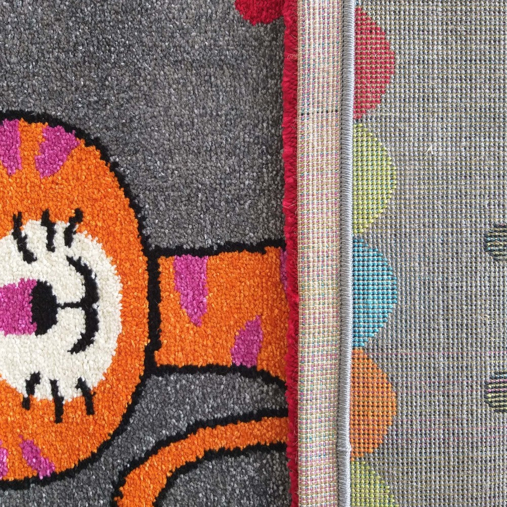 Tapis gris shaggy avec un motif stylisé orange, rose et noir, et son revers tissé à pois multicolores