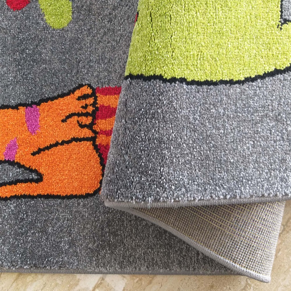 Tapis gris à motifs colorés orange, vert anis, rose et rouge. Il est roulé, laissant voir sa texture moelleuse et son envers tissé