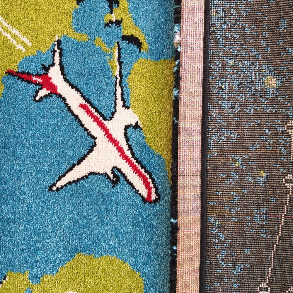 Tapis à poils courts. Sa surface affiche un motif de carte du monde bleu et vert orné d'un avion blanc et rouge. Sur le côté droit, le revers tissé du tapis apparaît avec des points bleus et jaunes