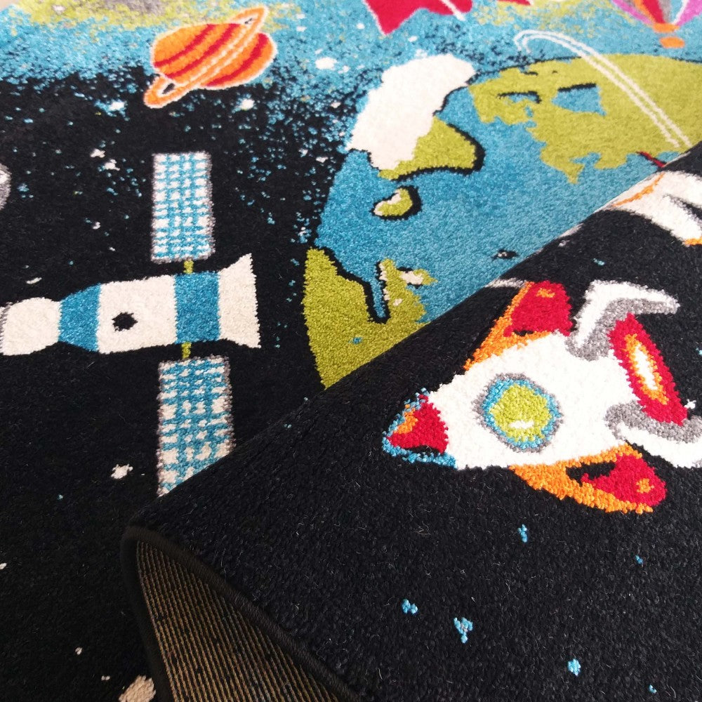 Tapis à fond noir représentant l'espace avec la Terre bleue et verte, une fusée, un satellite et une planète orange. Une section est repliée