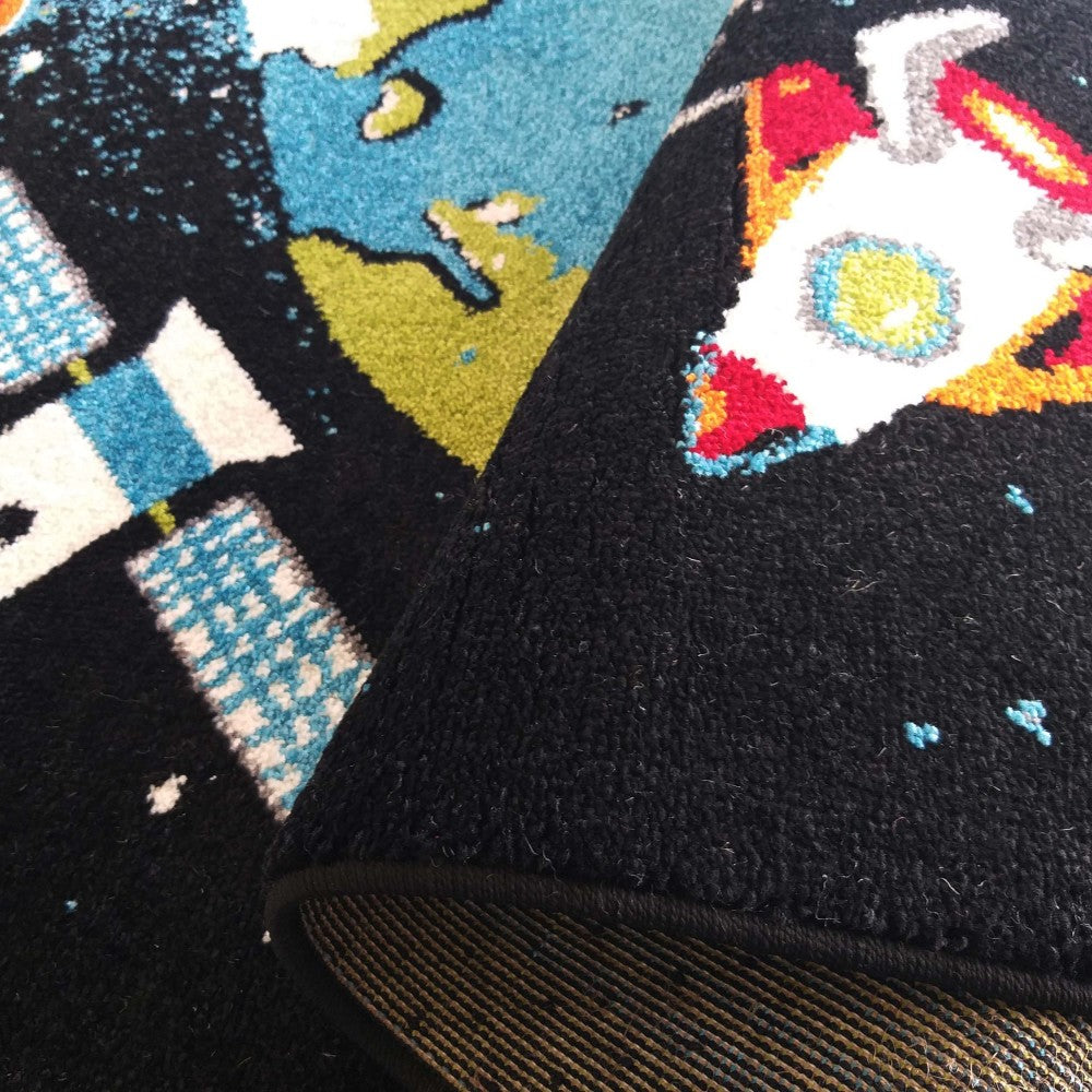 Tapis moelleux noir aux motifs colorés: fusée blanche, planètes bleues et vertes, et damiers blancs et bleus