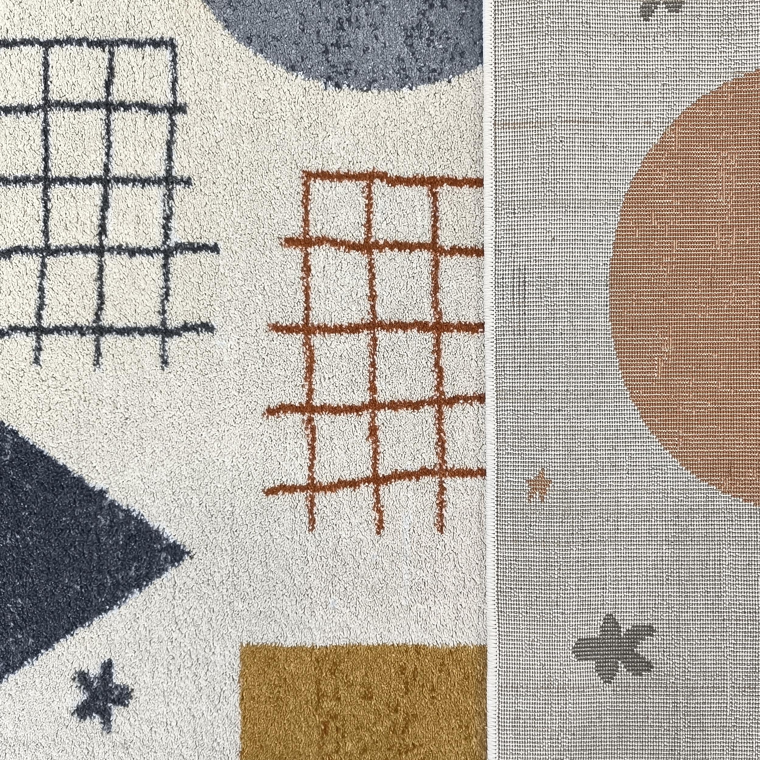 Tapis bouclé blanc cassé aux motifs abstraits colorés, avec un revers tissé montrant un cercle orange et des étoiles