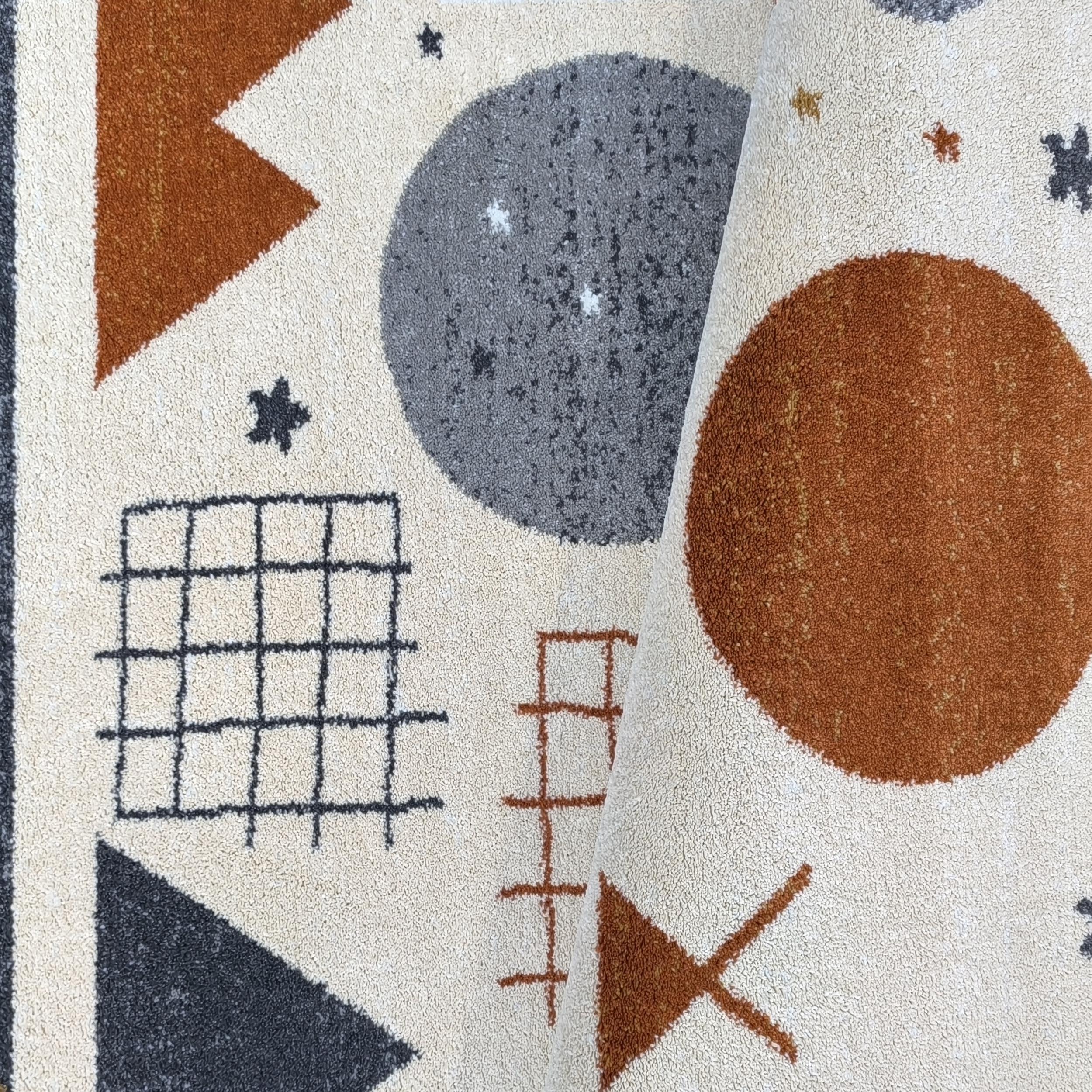 Tapis crème à motifs géométriques abstraits en orange rouille et gris anthracite, partiellement enroulé