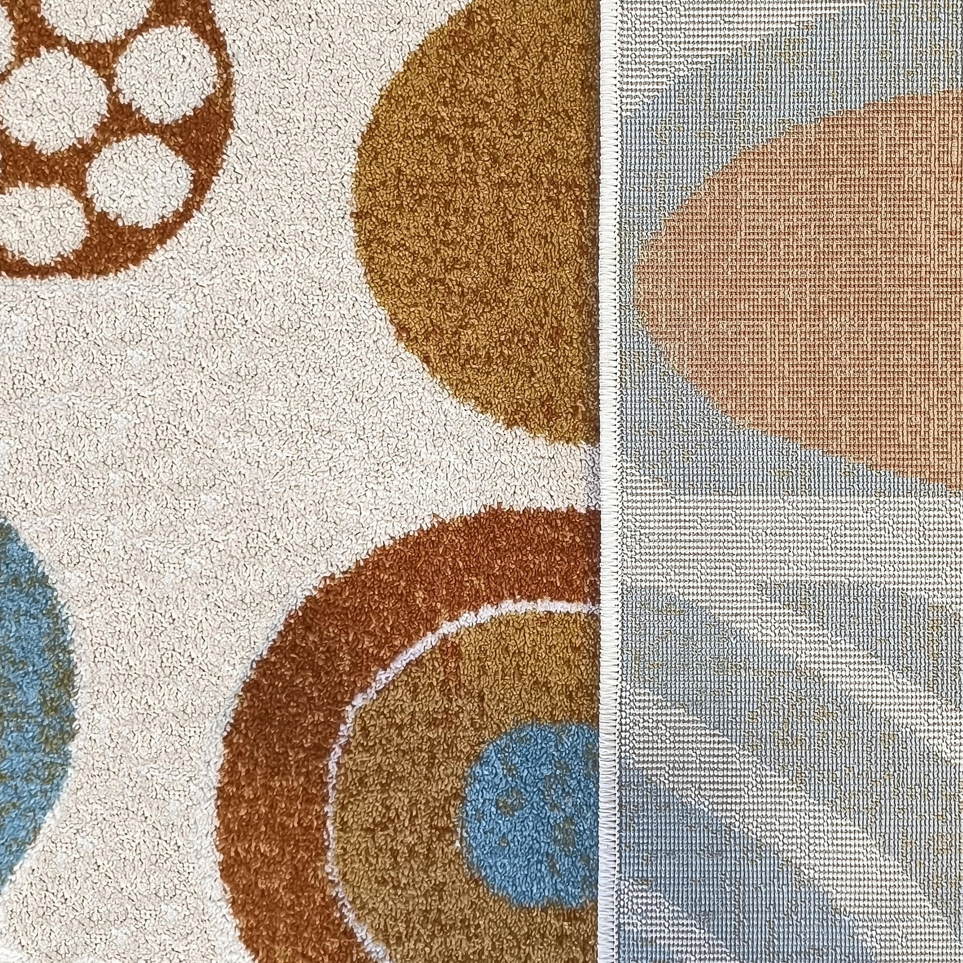 Tapis moelleux aux motifs de cercles crème, marron et bleu clair, montrant aussi son envers tissé