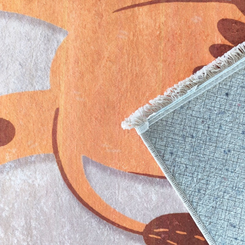Tapis aux motifs orange, blancs et marron avec une texture douce. Un coin est soulevé, montrant le dessous antidérapant bleu et des franges blanches