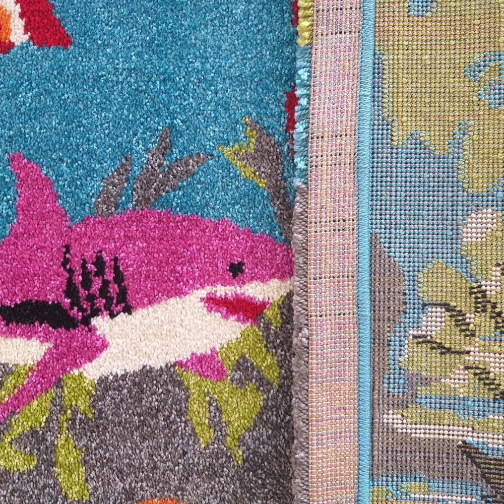 Gros plan sur deux tapis. Un tapis rose et bleu à poils longs avec un requin, l'autre à motifs verts, bleus et gris