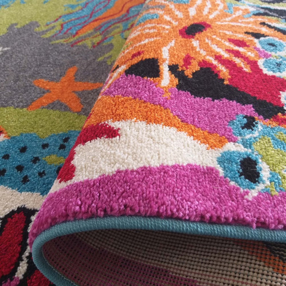 Tapis moelleux roulé, aux motifs marins stylisés et couleurs vives : fuchsia, orange, bleu, vert et gris