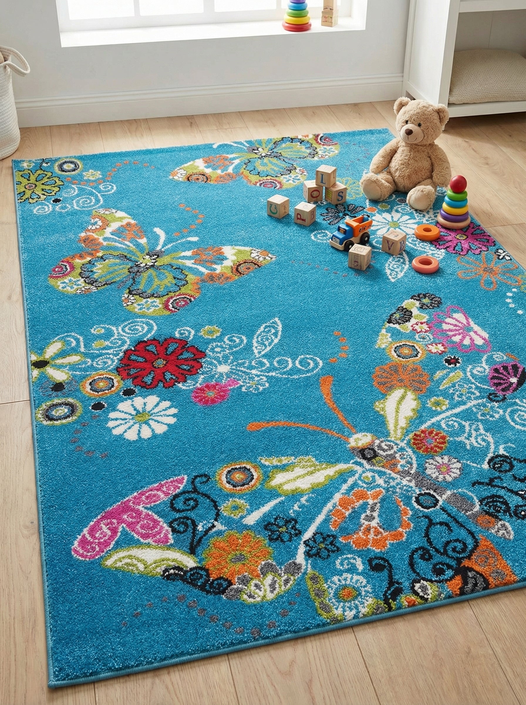 Tapis rectangulaire à poils courts, bleu turquoise vif, orné de grands papillons et de fleurs multicolores joyeuses, dans une chambre d'enfant