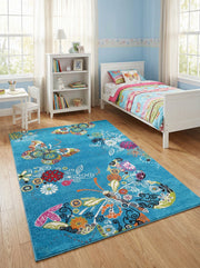 Tapis rectangulaire turquoise avec des motifs vifs de papillons et de fleurs colorées sur un sol en bois clair dans une chambre d'enfant