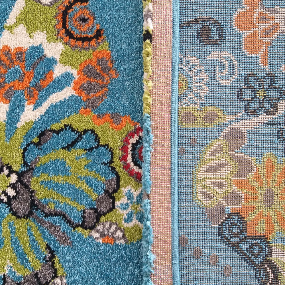 Tapis à motifs floraux et cachemire bleu turquoise, orange et vert anis. Il combine une texture moelleuse et une partie tissée