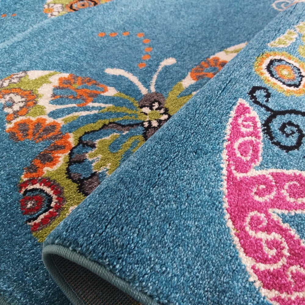 Un tapis bleu turquoise à motifs de papillons multicolores en rose, orange, vert, blanc et gris, avec une texture douce
