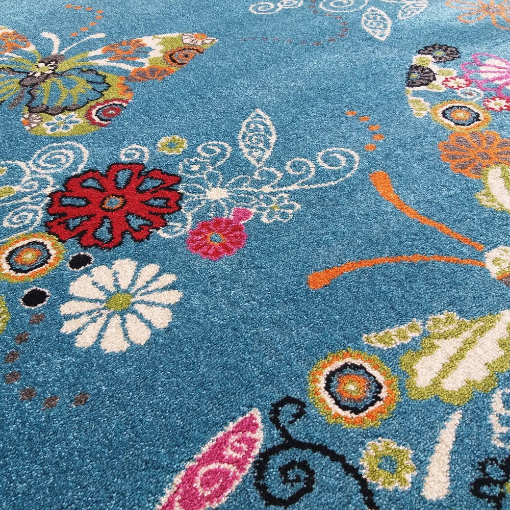 Tapis bleu turquoise doux avec de grands motifs floraux et des papillons multicolores aux couleurs vives