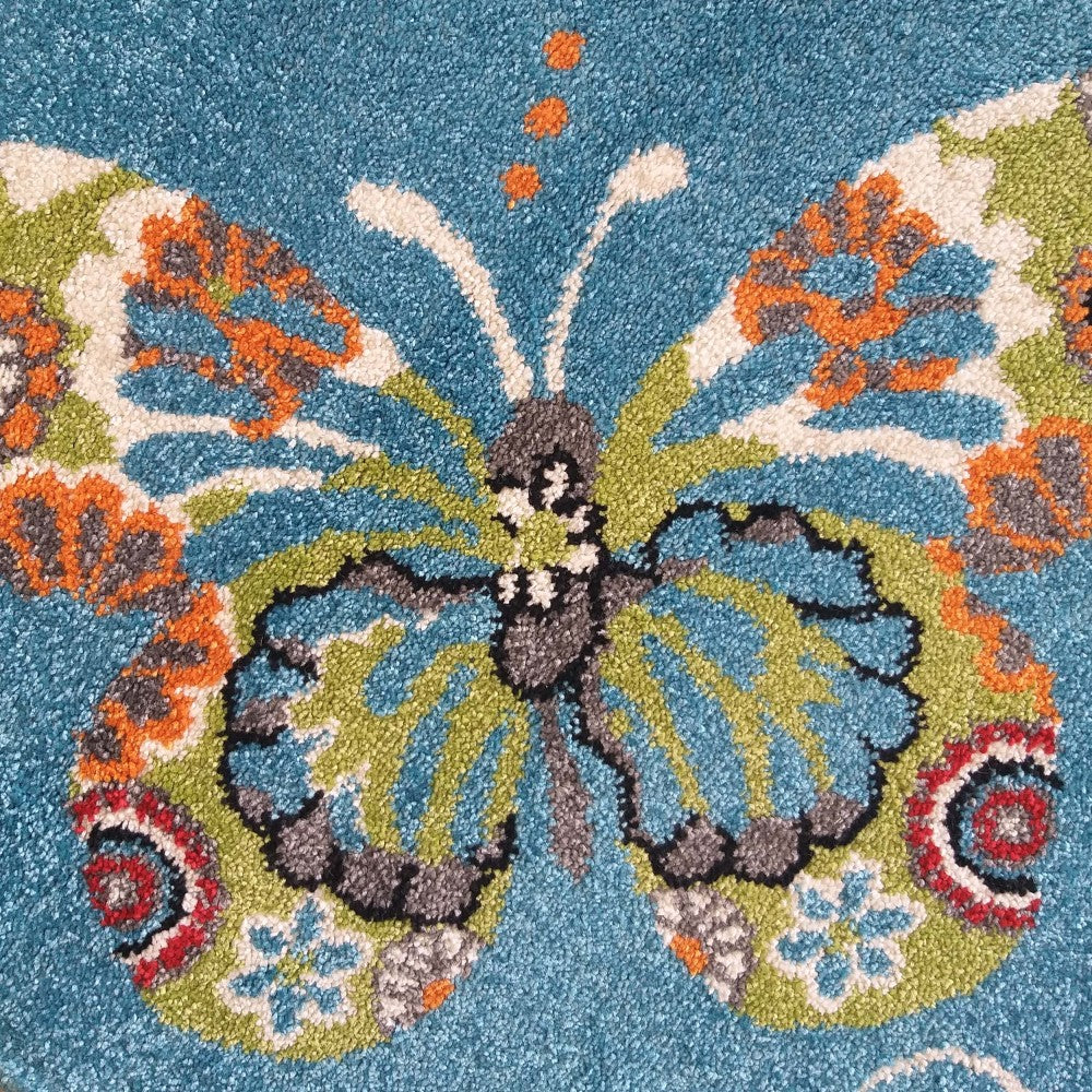 Tapis bleu vif à texture bouclée, orné d'un grand papillon aux motifs verts, bleus, oranges et blancs