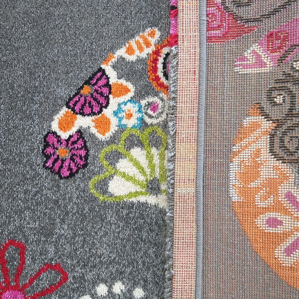 Gros plan sur un tapis gris aux motifs colorés floraux et ornementaux, montrant la surface et le revers