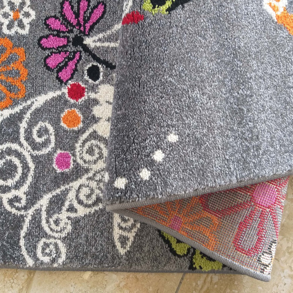 Tapis gris à motifs floraux et volutes multicolores avec son dessous uni gris et l'envers tissé aux motifs roses et oranges