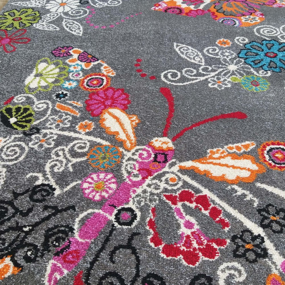 Tapis gris foncé orné de motifs floraux et de papillons aux couleurs vives : rose, orange, rouge, blanc, vert et bleu