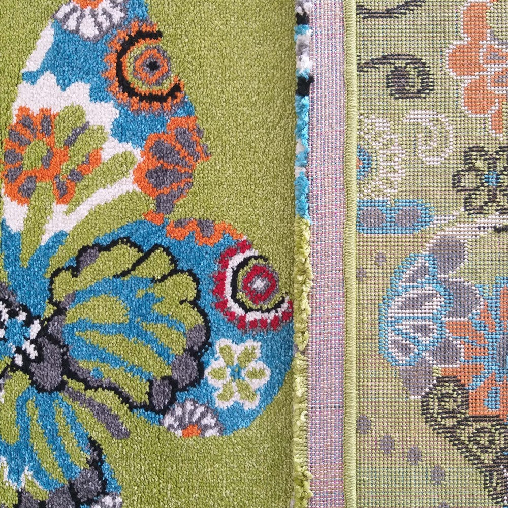Un tapis vert à poils longs avec un grand motif papillon bleu, orange, blanc, gris et noir est juxtaposé à un tapis tissé à motifs floraux vert clair