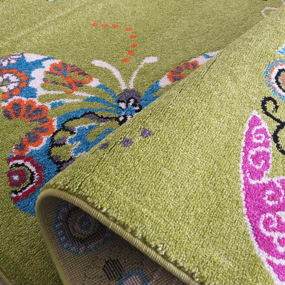 Tapis vert clair avec des motifs de papillons colorés en bleu, orange, blanc et rose. Sa texture de poils courts est visible