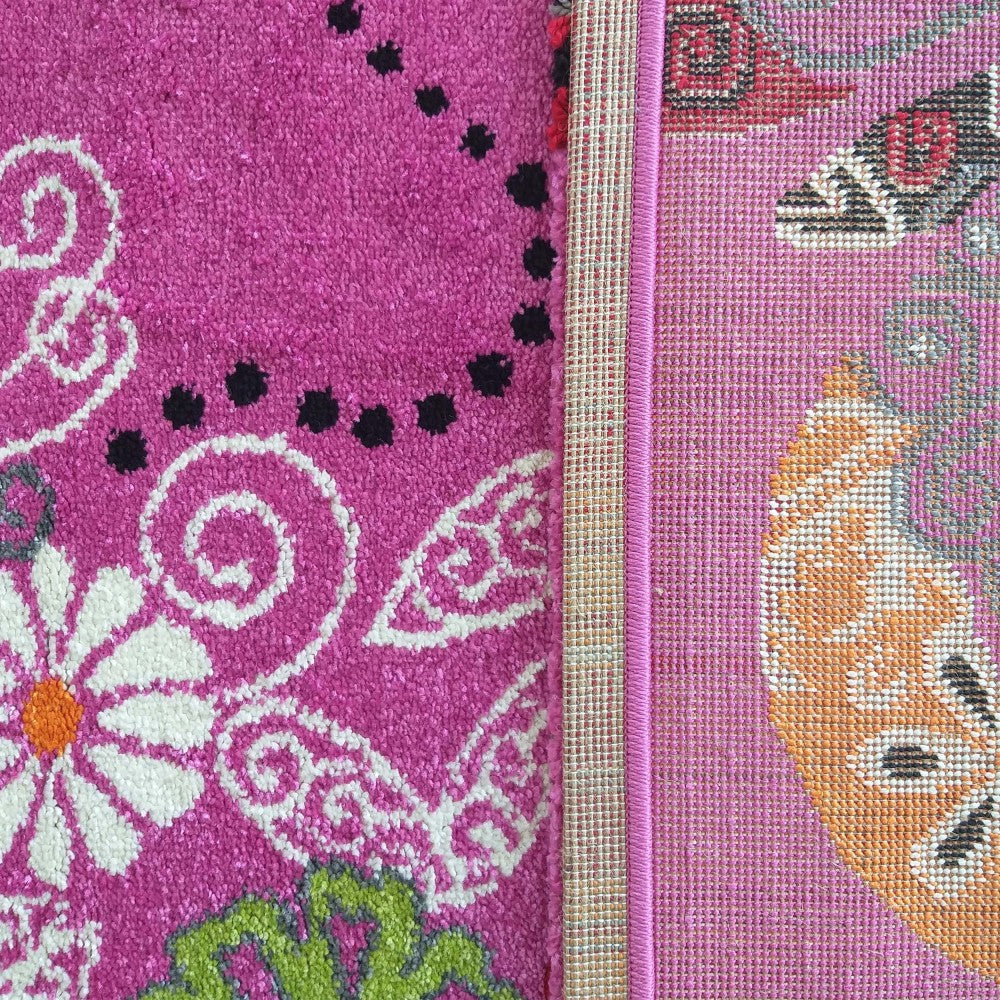 Tapis rose fuchsia à poils ras avec motifs floraux blancs et noirs, montrant son envers tissé aux motifs oranges et gris