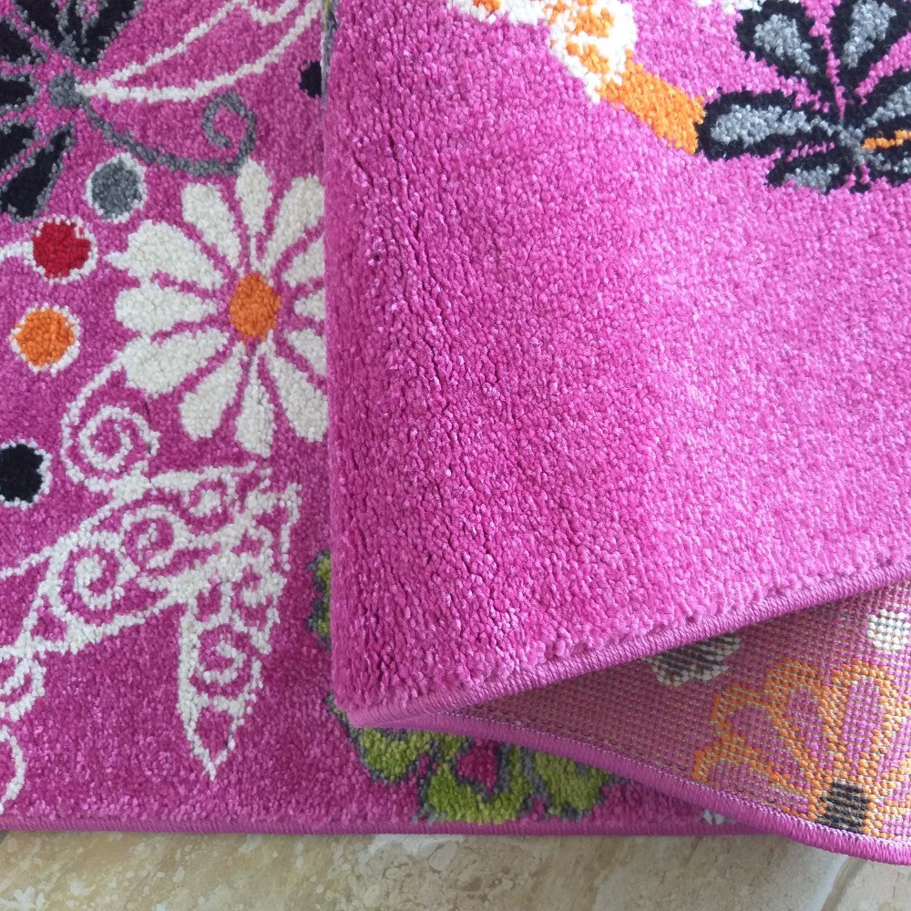 Tapis fuchsia à poils courts, avec motifs de marguerites blanches, papillons noirs et gris, et volutes. Le tapis est replié, montrant sa surface douce et son envers tissé