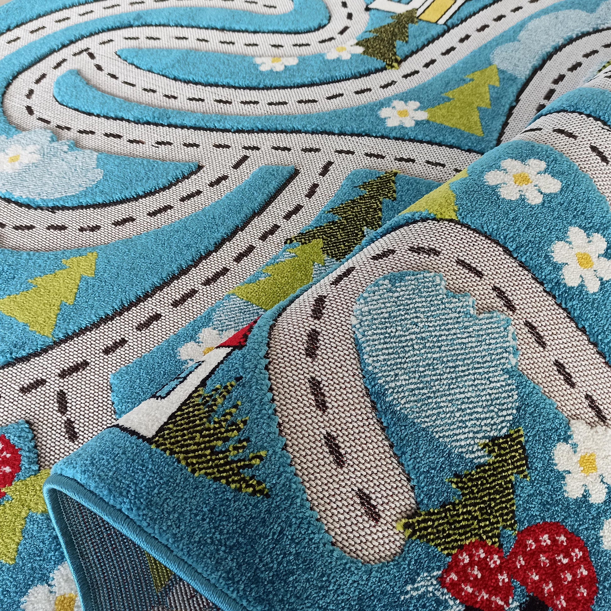 Tapis en relief bleu ciel avec des routes blanches, des arbres verts, des nuages, des fleurs marguerites et des champignons rouges