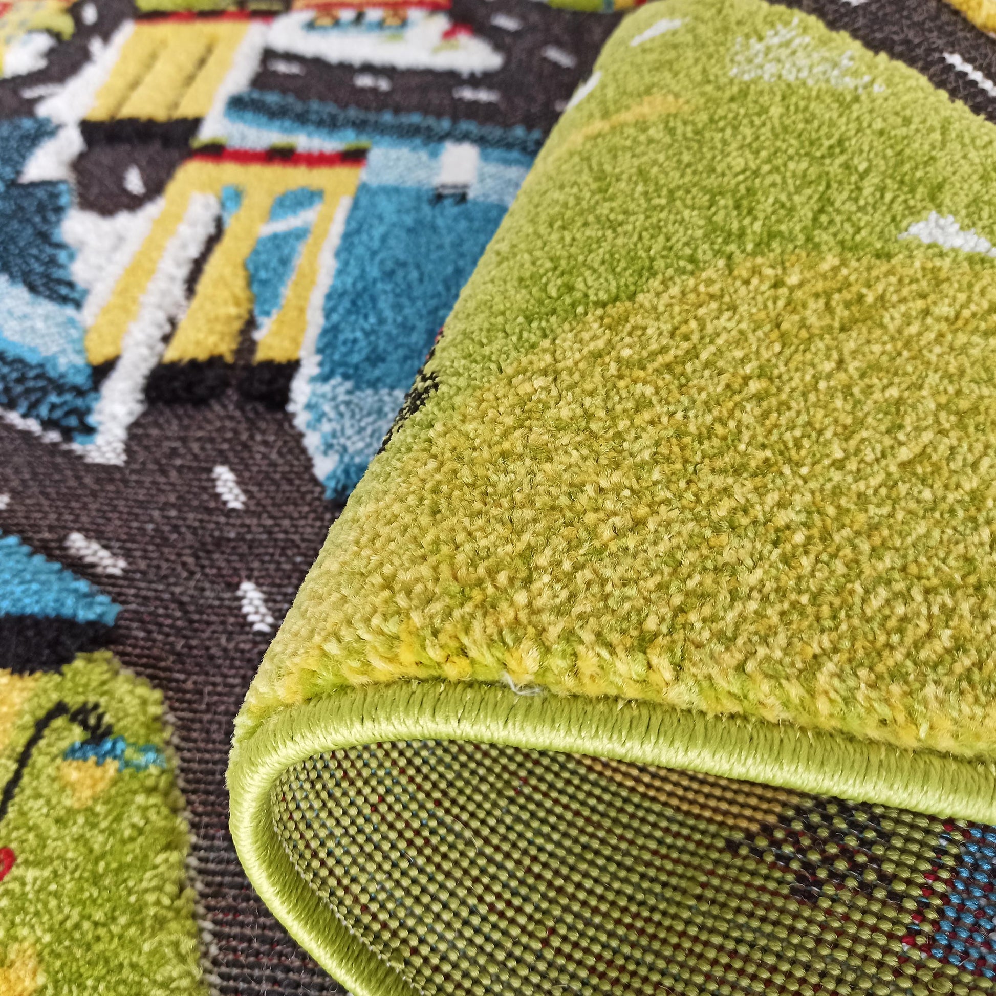 Gros plan sur un tapis enroulé, révélant sa surface à poils courts vert vif et son dessous tressé aux motifs colorés bleus, jaunes et bruns