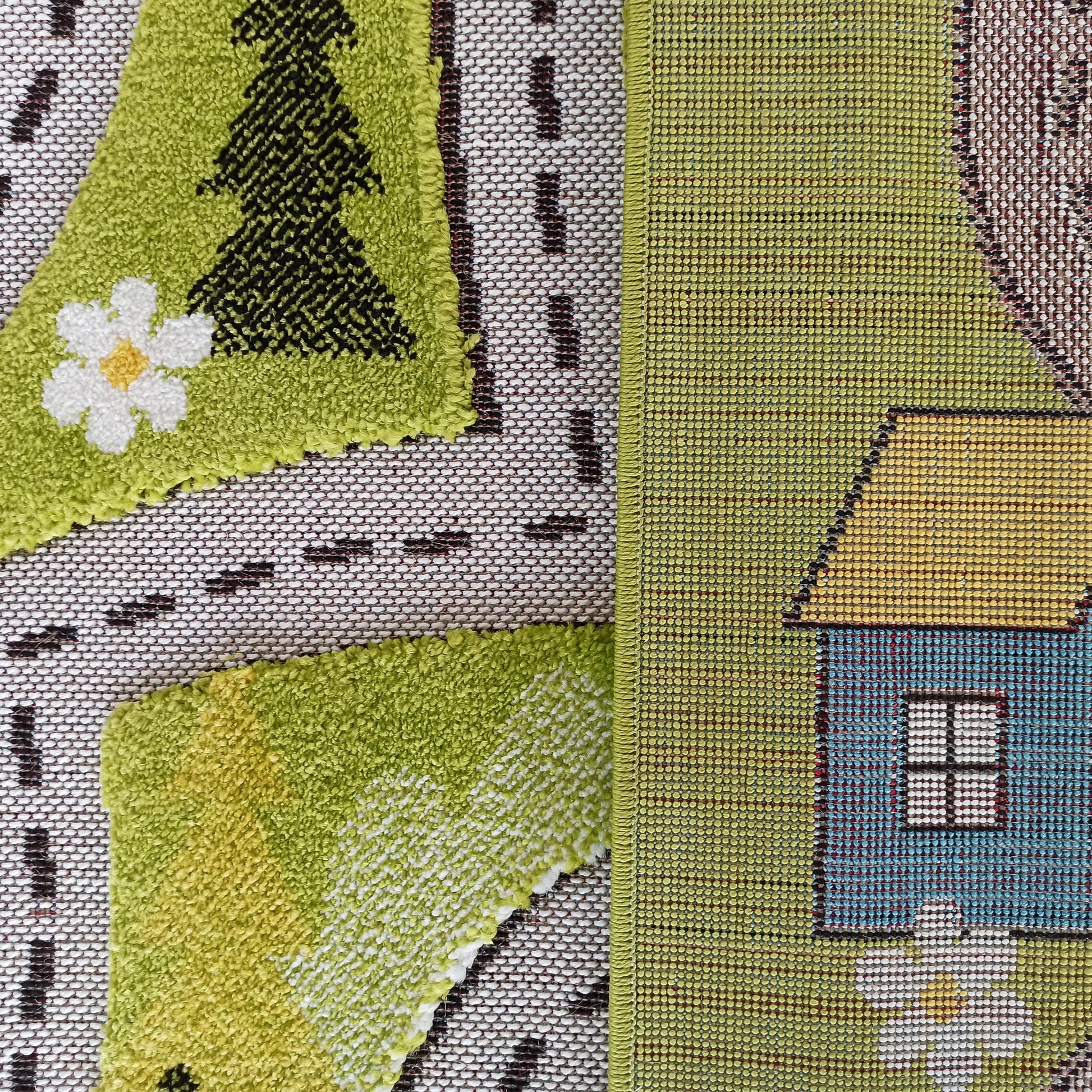 Tapis aux textures variées, représentant une scène avec route pointillée, arbre vert, fleur blanche et maison bleue et jaune