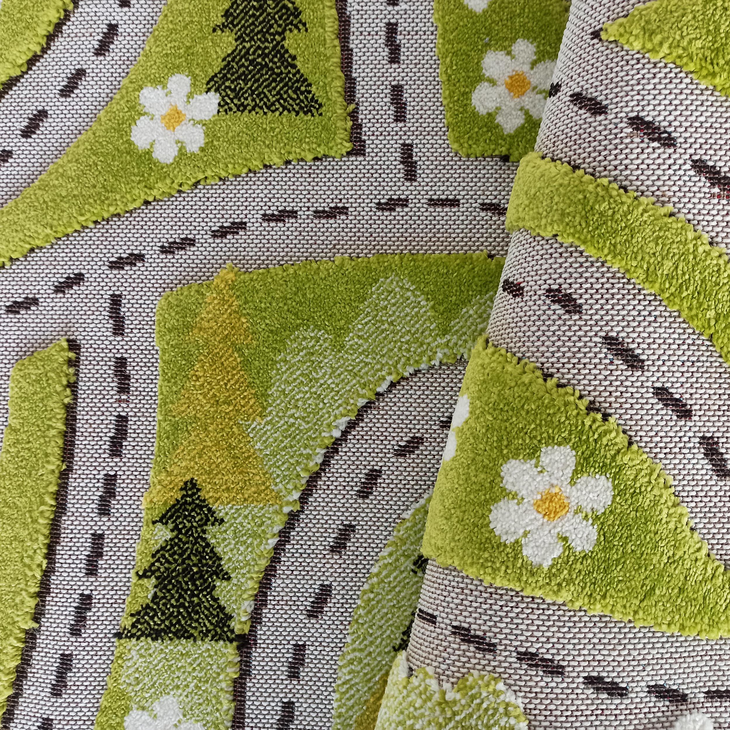 Tapis vert à la texture bouclée, orné de routes sombres, d'arbres et de fleurs blanches à cœur jaune, en partie enroulé