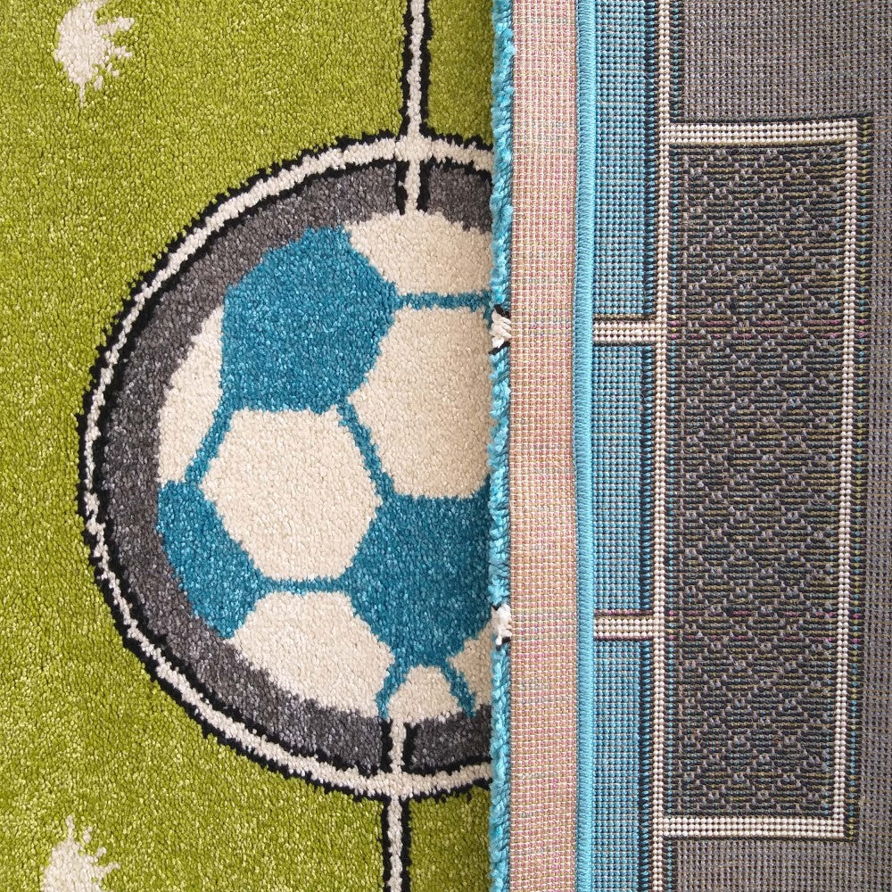 Tapis vert texturé orné d'un motif de ballon de football bleu et blanc. Le revers du tapis, tissé gris avec des bordures bleues, est visible