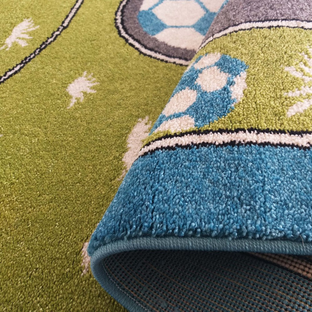 Tapis moelleux vert et bleu à motifs de ballons de football blancs et gris, partiellement roulé, montrant son envers antidérapant