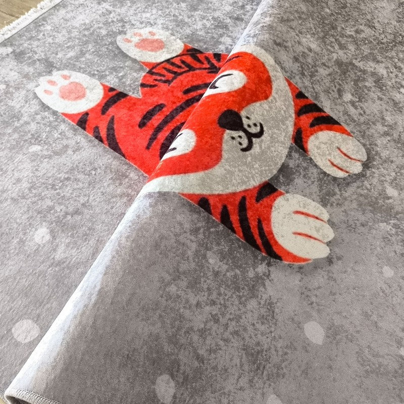 Tapis gris moucheté présentant un motif de tigre de dessin animé orange et noir avec des pattes blanches et roses, partiellement roulé