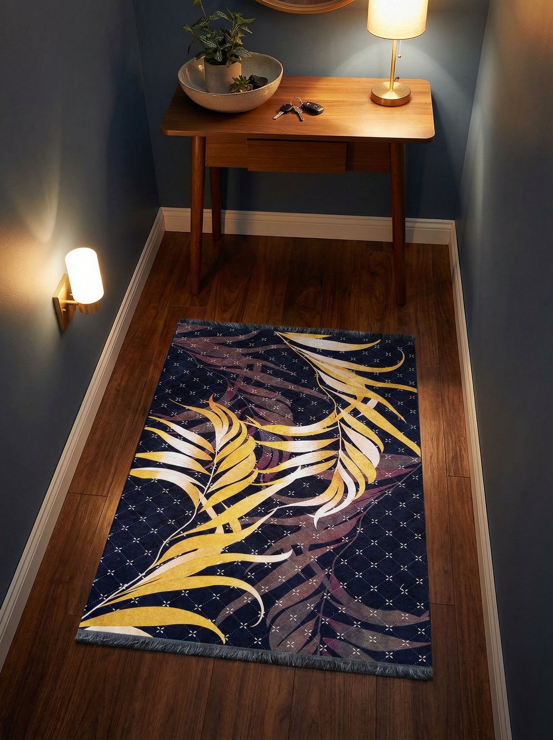 Tapis rectangulaire bleu marine à motifs de grandes feuilles jaunes, blanches et pourpres sur fond quadrillé, avec franges, posé sur parquet d'entrée
