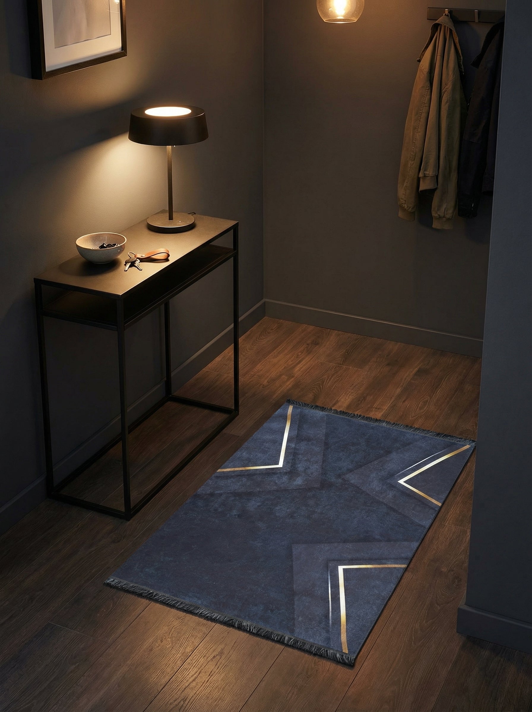 Tapis rectangulaire bleu nuit texturé avec des motifs géométriques dorés et franges, posé sur un parquet dans une entrée moderne