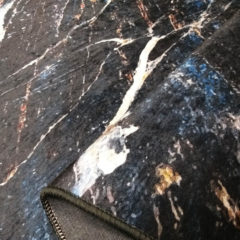 Tapis à la texture douce orné d'un motif marbre sombre avec des veines blanches, bleues et des touches dorées, un bord ourlé visible