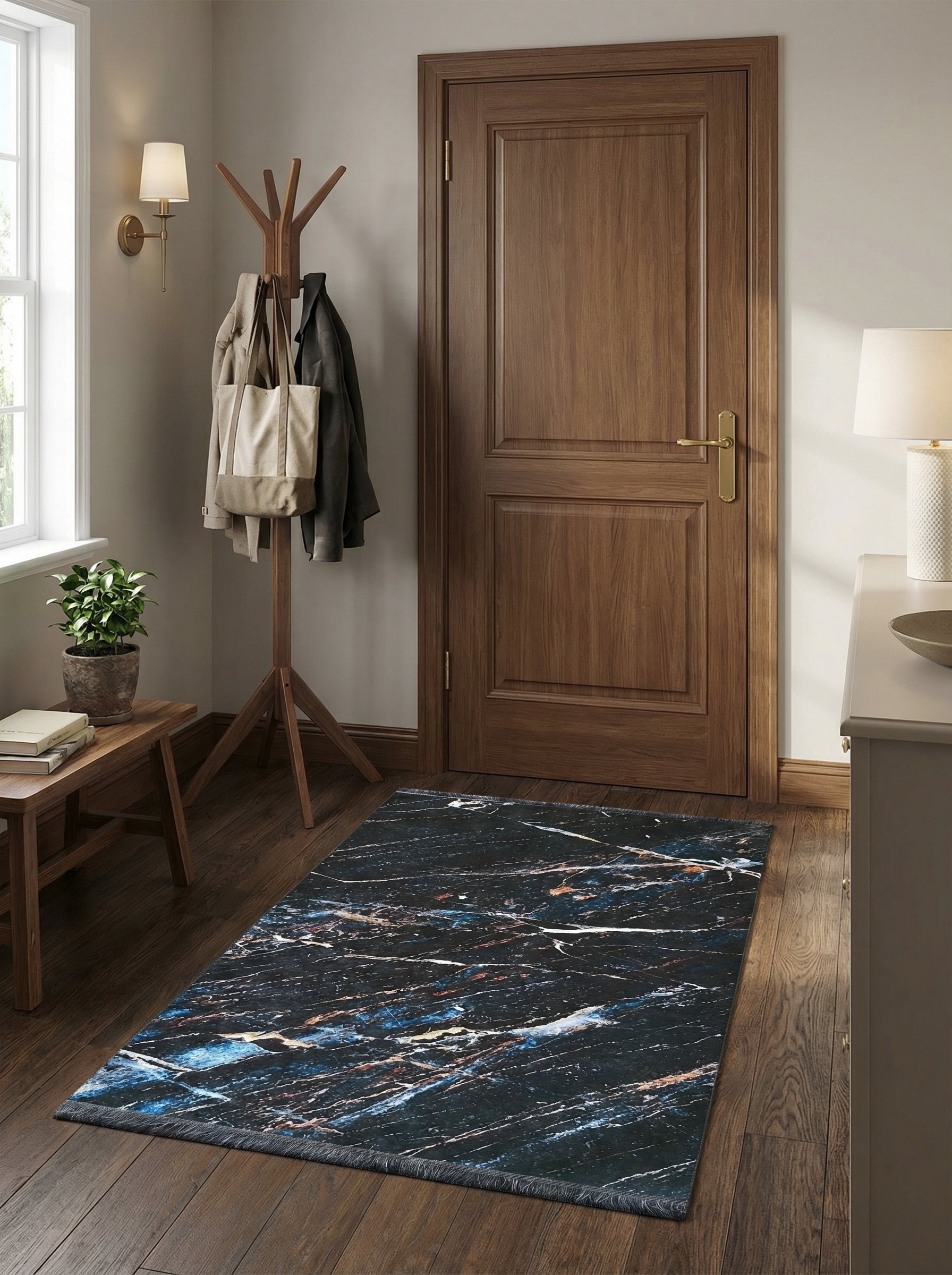 Tapis rectangulaire à motifs marbrés noirs, bleus, blancs et cuivrés, avec des franges discrètes dans une entrée