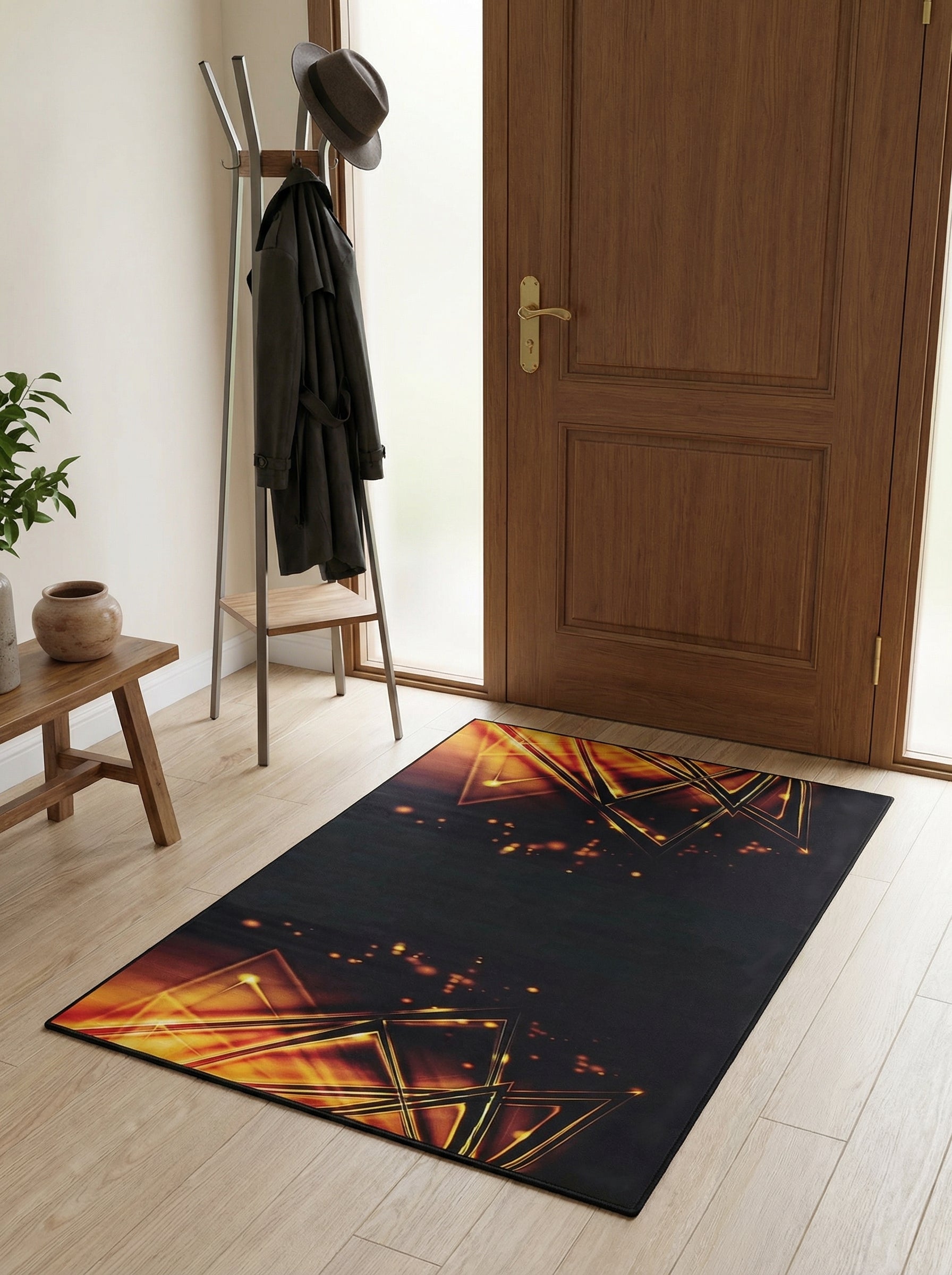 Tapis noir rectangulaire avec des motifs lumineux de triangles dorés et oranges, sur un parquet clair d'entrée