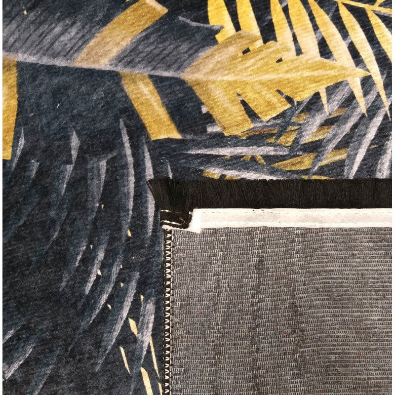 Tapis à motif de grandes feuilles tropicales bleu foncé et jaune doré, avec une bordure noire frangée et l'envers gris texturé visible