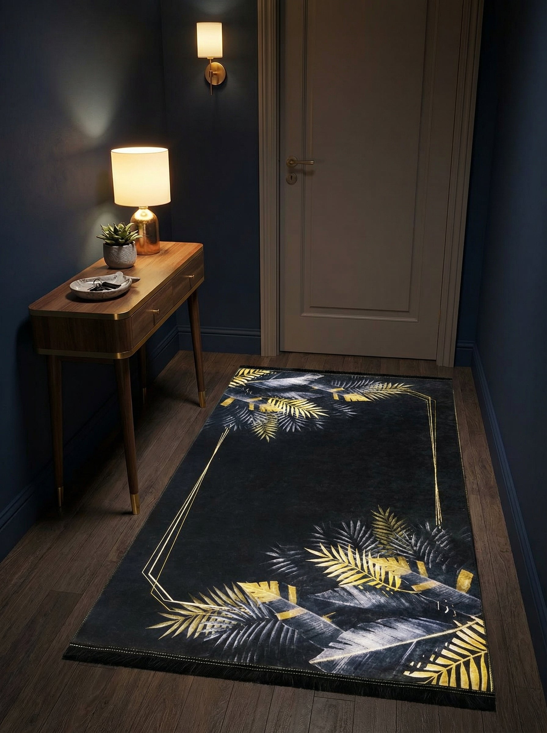 Tapis rectangulaire à motifs de feuilles tropicales dorées et grises sur fond noir, avec un cadre géométrique doré, dans une entrée sombre