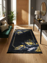 Tapis rectangulaire noir orné de feuilles tropicales dorées et grises, avec un cadre géométrique doré, posé dans une entrée moderne