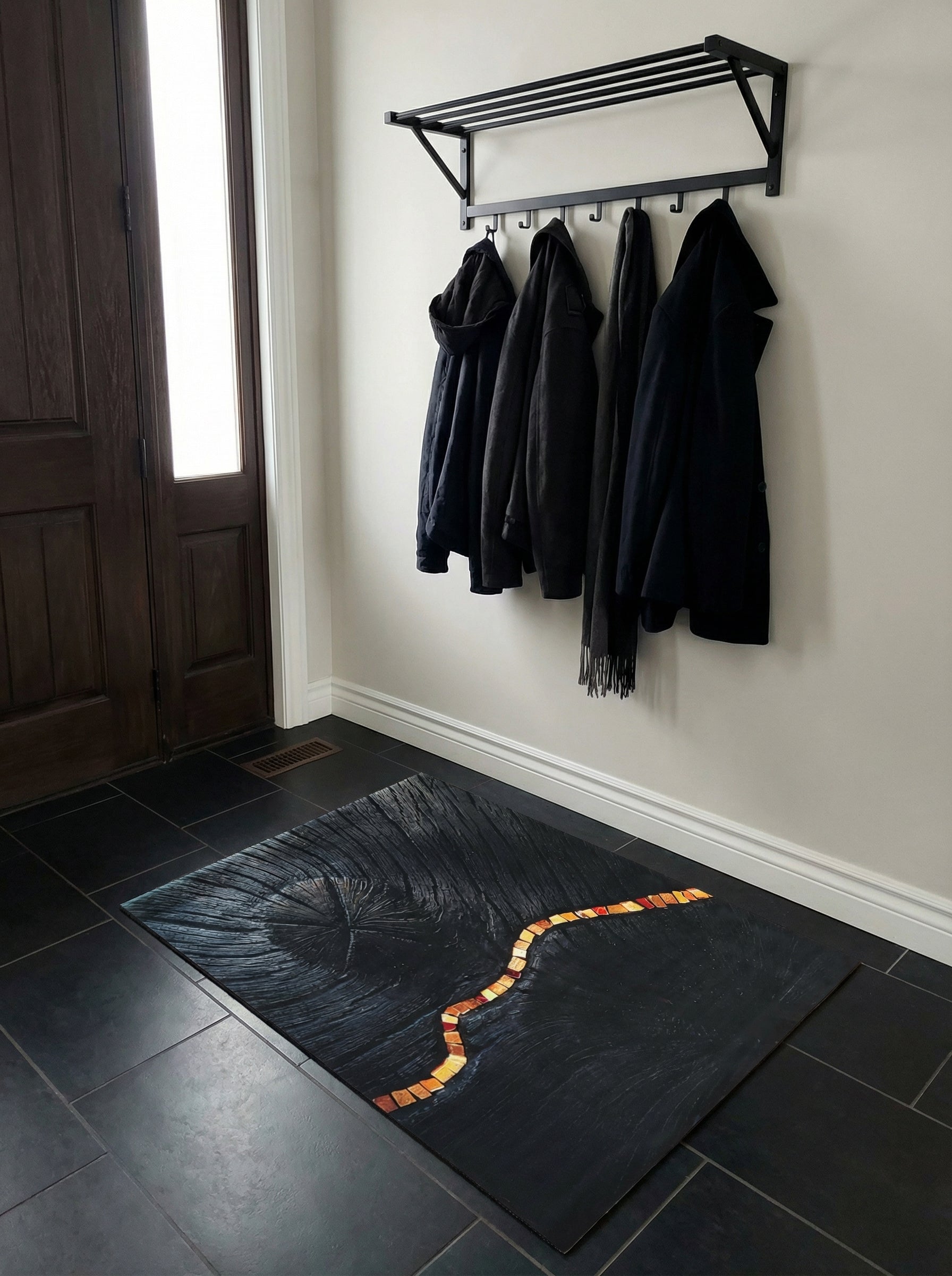 Tapis rectangulaire gris anthracite, motif cernes de bois et bande sinueuse de mosaïque rouge-orangée, dans une entrée