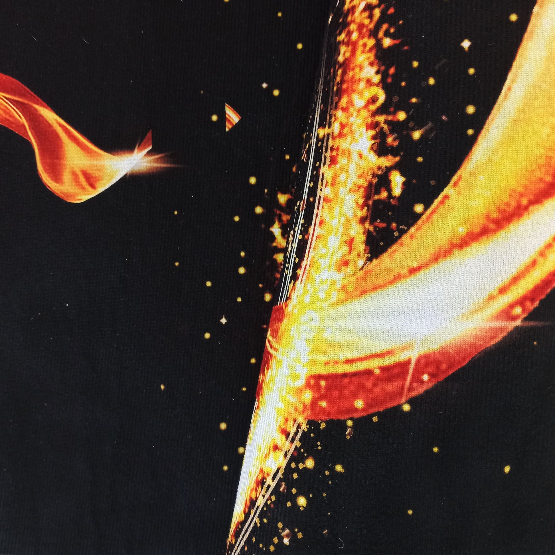 Tapis à fond noir présentant un motif abstrait flamboyant de couleurs orange, rouge et jaune vif, parsemé de points lumineux