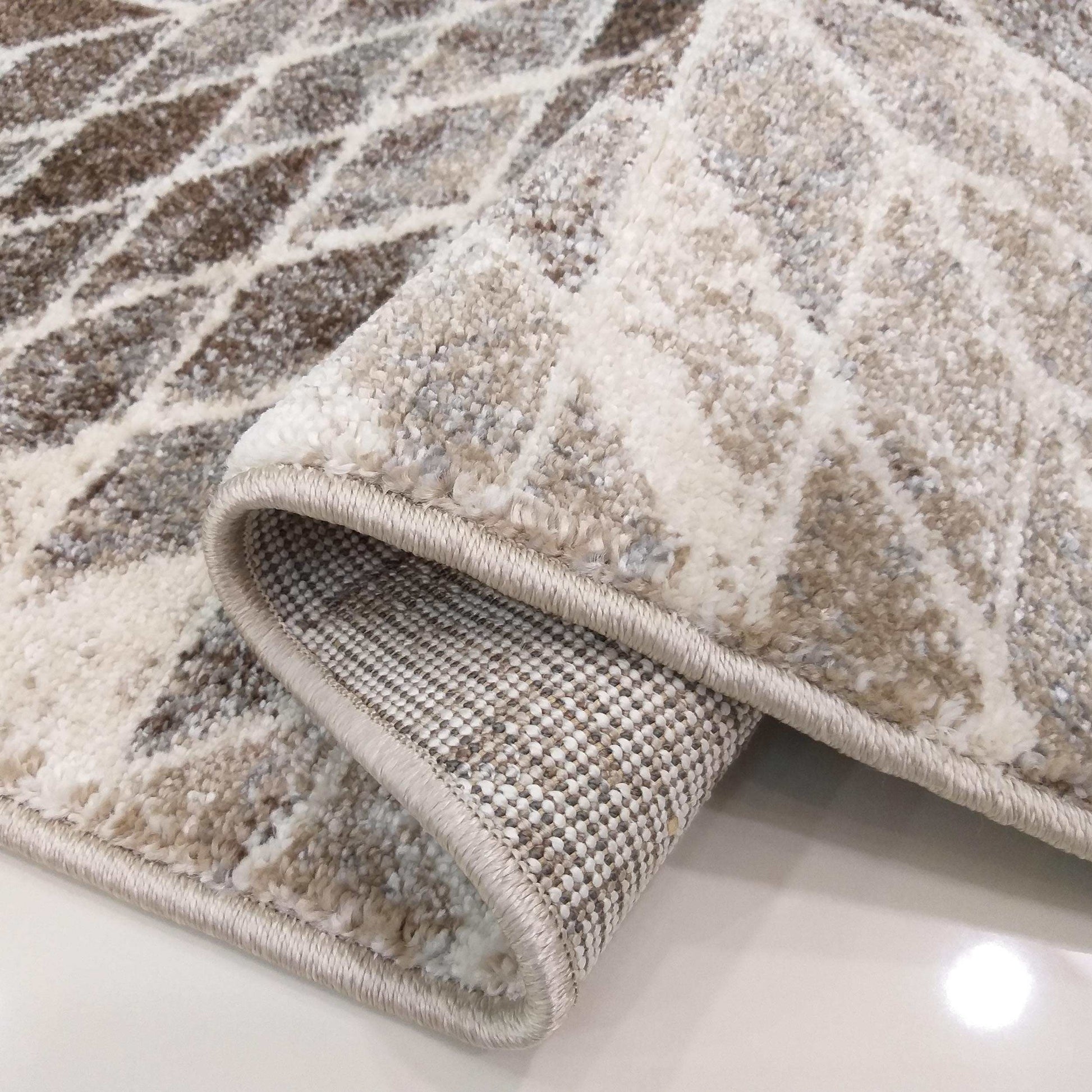 Tapis moelleux aux motifs géométriques marron, beige et blanc cassé, avec revers tissé et bordure beige