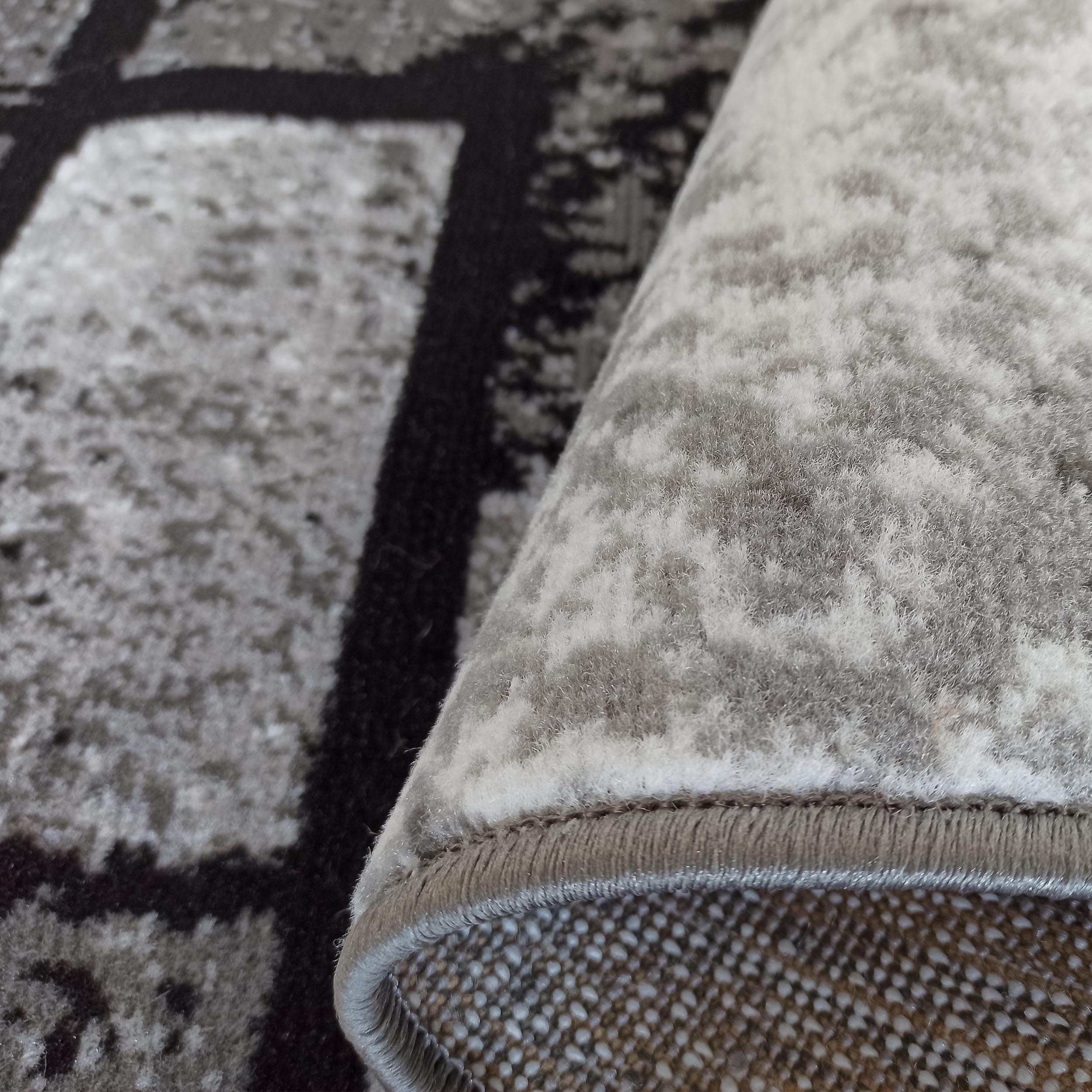 Tapis gris, noir et blanc à motifs géométriques et texture douce, au revers brun clair pointillé de blanc