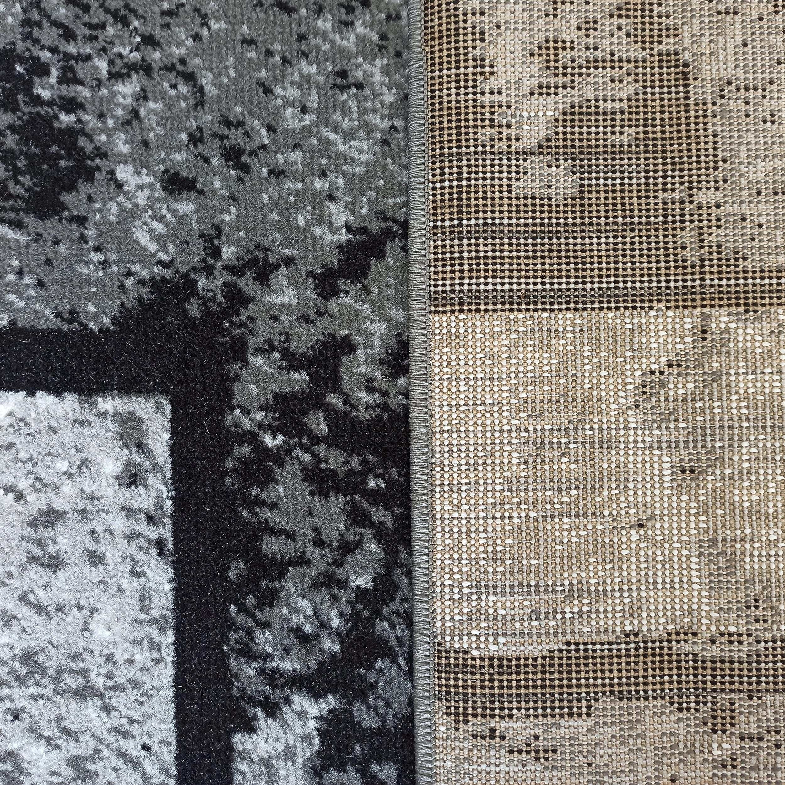 Tapis à poils moucheté gris, noir et blanc, son envers tissé beige et marron à petits points, unis par une couture grise