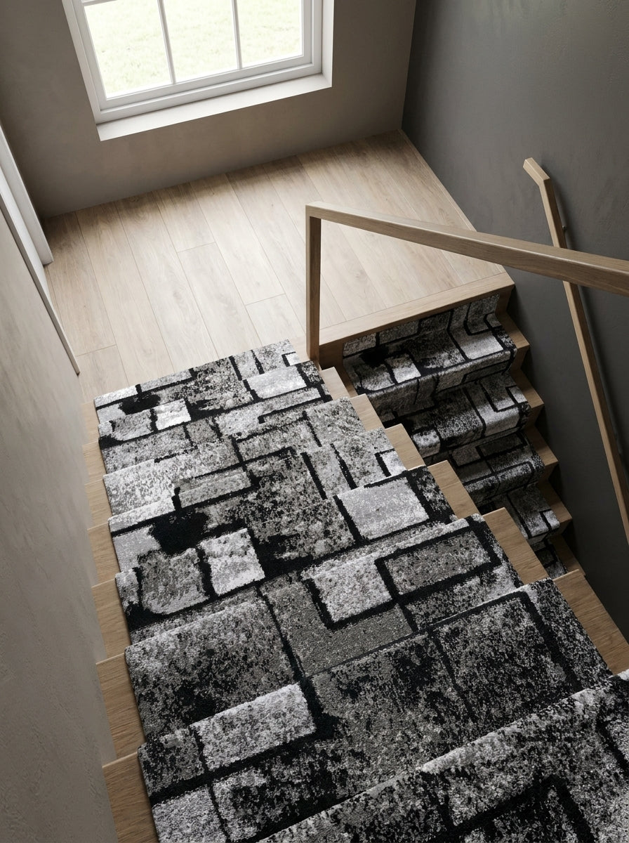 Tapis d'escalier noir, gris, blanc à motifs géométriques sur escalier en bois clair dans entrée lumineuse