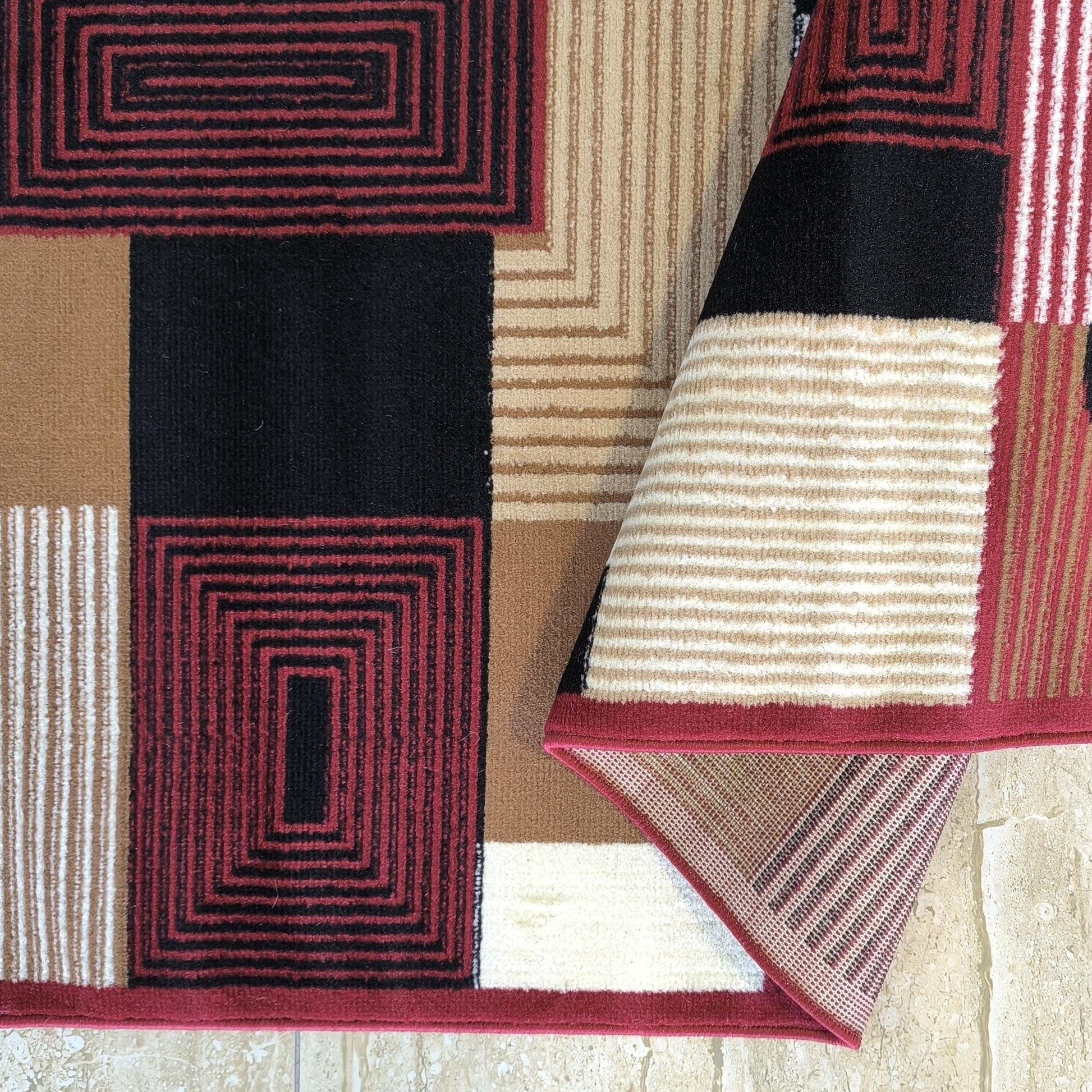 Tapis aux motifs géométriques noir, rouge, beige et crème, avec rayures et rectangles concentriques, un coin plié